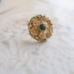 22kt gold ring studded with emeralds and diamonds, handcrafted with elegant traditional detailing.