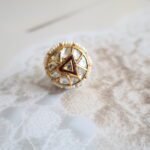 22kt gold Rakhri with diamond polkies, freshwater pearls, and detailed back enamelling, handcrafted in traditional design.