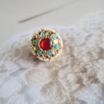 Rakhri with firoza stones, diamond polkies, and rubies, handcrafted in traditional floral design for festive wear.