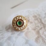 Rakhri with Kundan stones and antique-carved back, handcrafted with traditional detailing and symmetrical design.